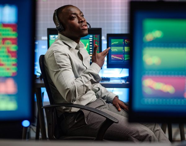Young African American man working in modern brokerage company having problems with his client trying to explain issue on phone