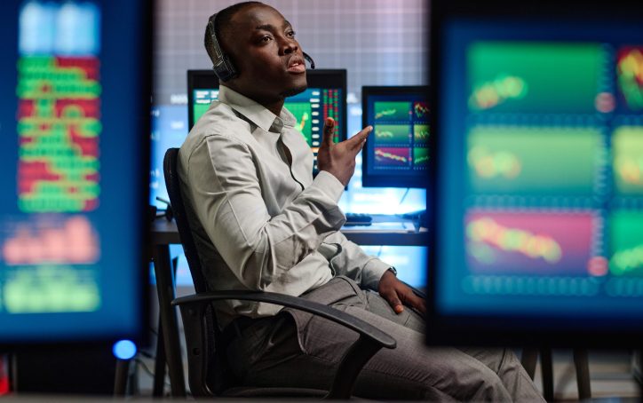 Young African American man working in modern brokerage company having problems with his client trying to explain issue on phone