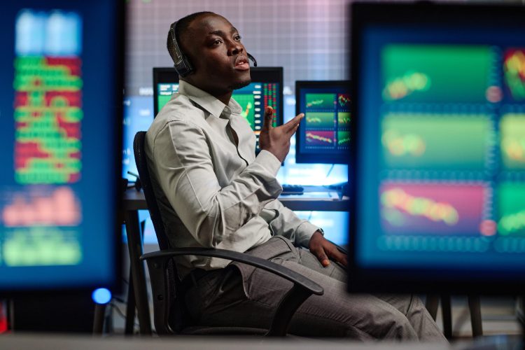Young African American man working in modern brokerage company having problems with his client trying to explain issue on phone