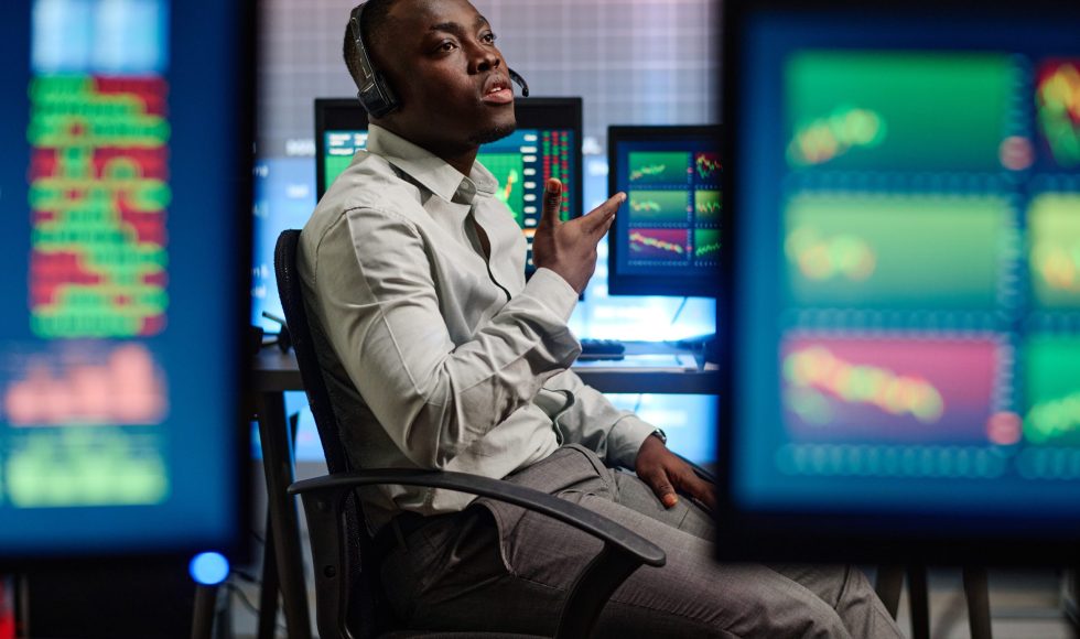 Young African American man working in modern brokerage company having problems with his client trying to explain issue on phone