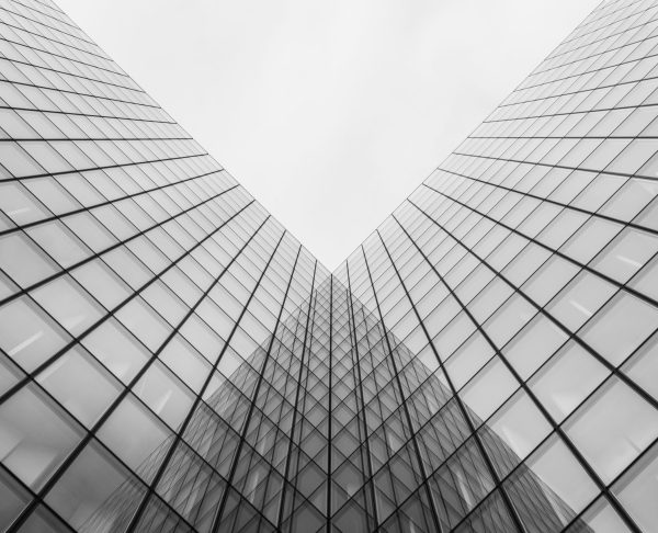 A grayscale shot of a modern building with glass walls