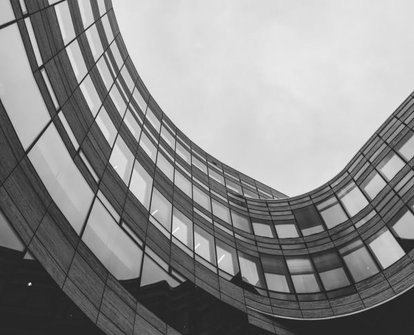 A low angle greyscale shot of a modern building captured on a cloudy day